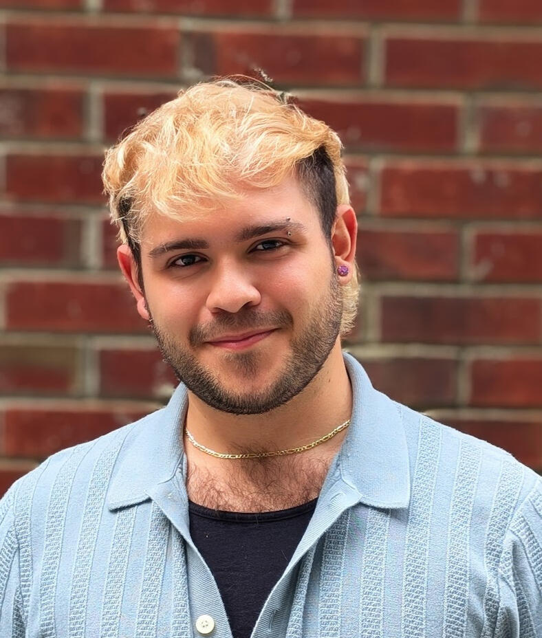 Headshot of voice actor Jorge Betancourt in front of brick wall.
